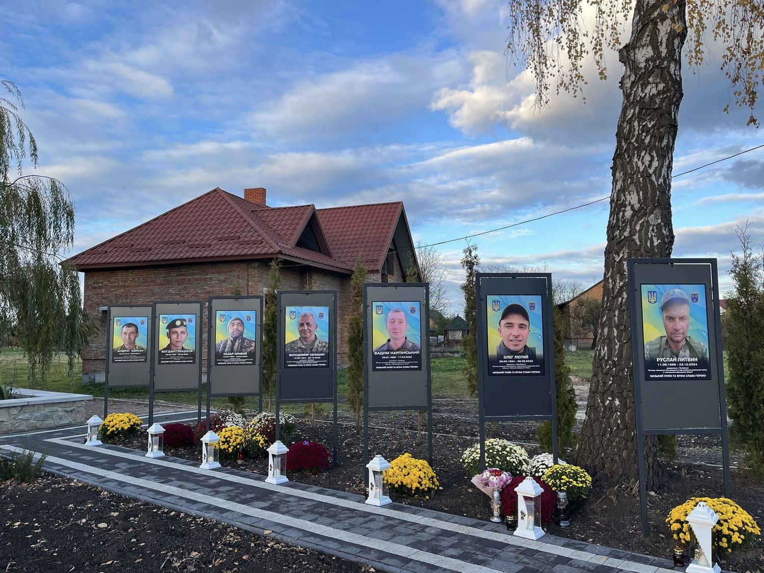 7 стендів на алеї героїв, внизу клумба з квітами