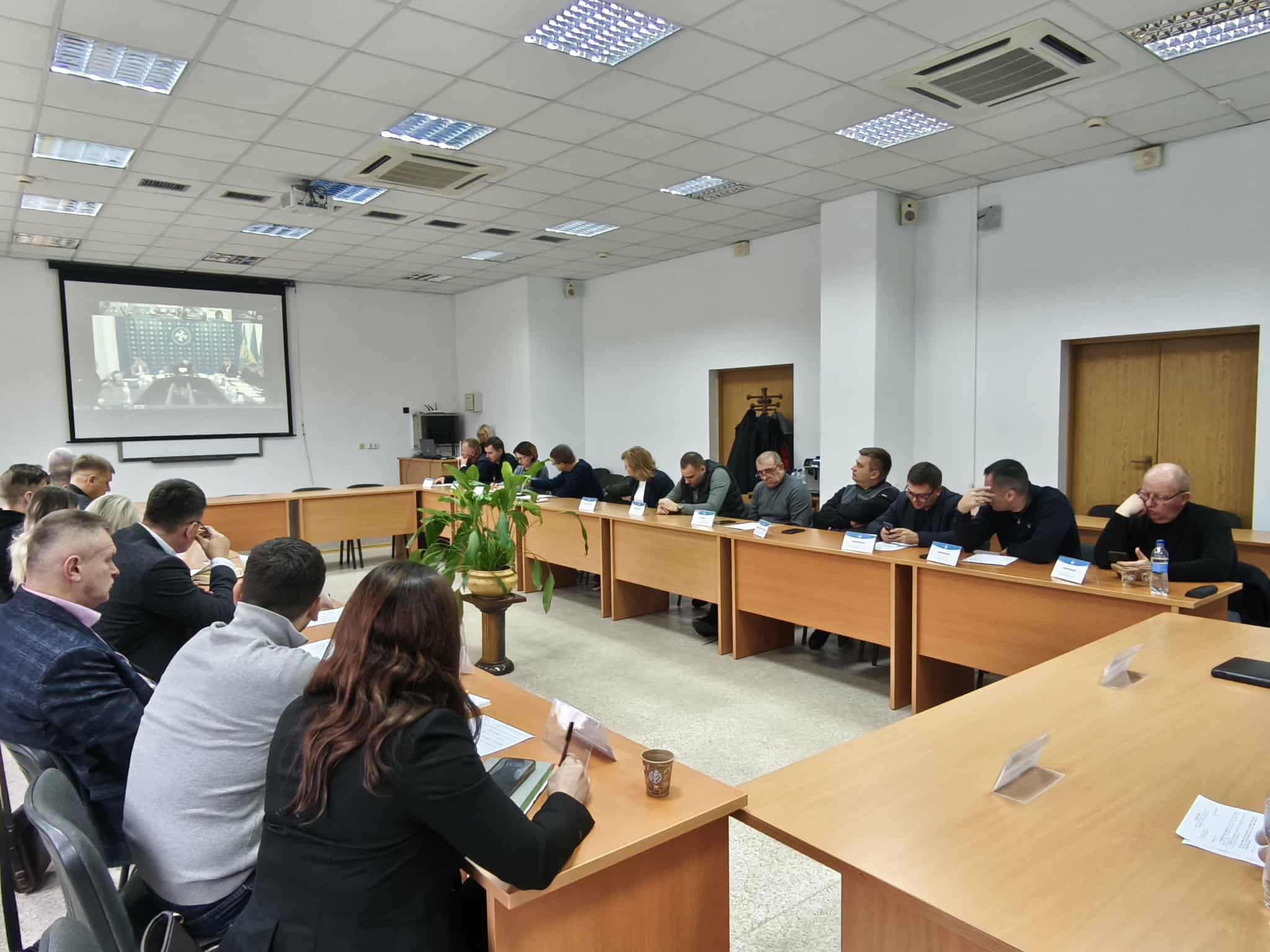 люди сидять в кабінету за столом, на стіні працює проєктор