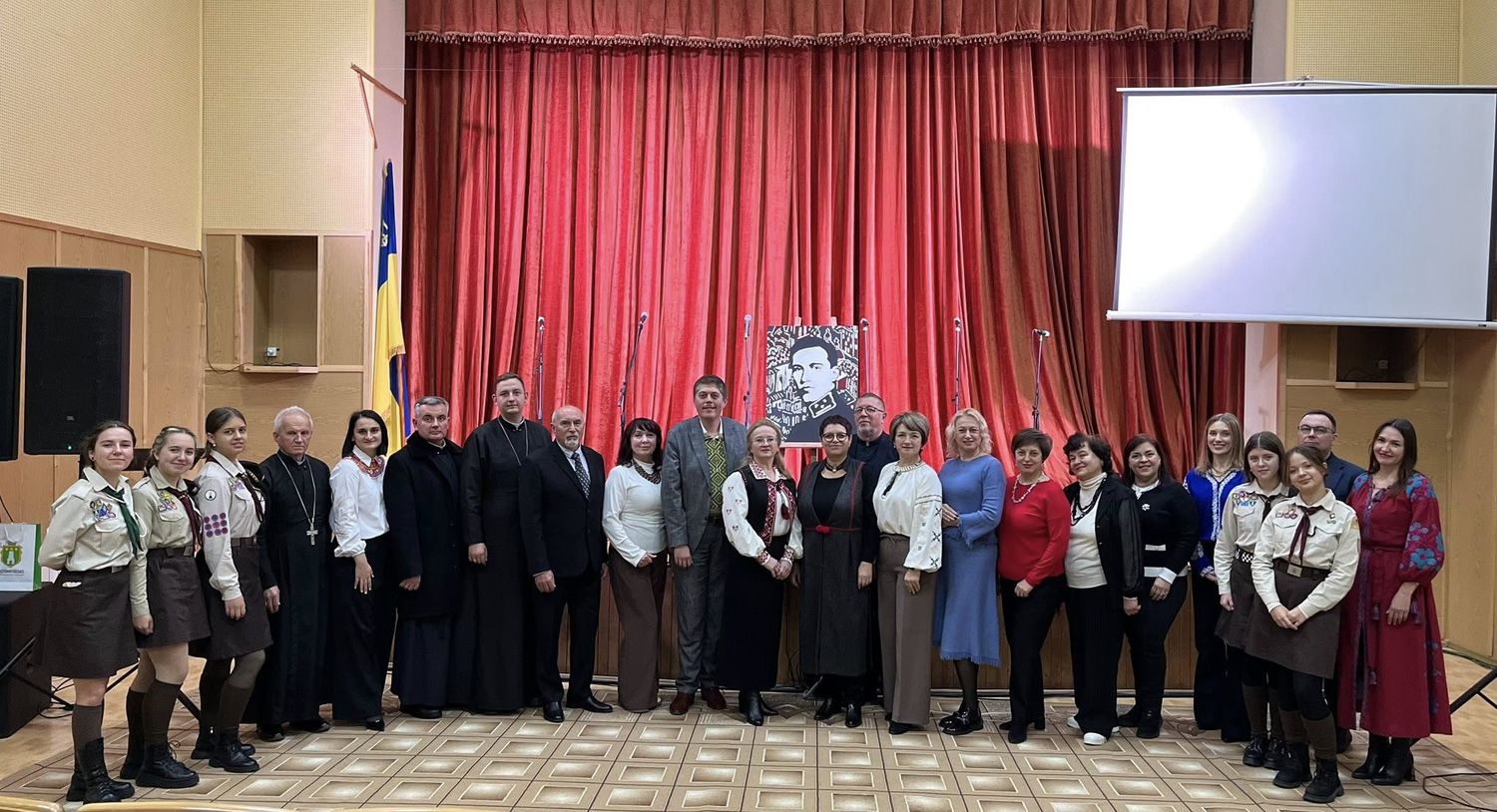 люди стоять перед сценою із червоною тканиною