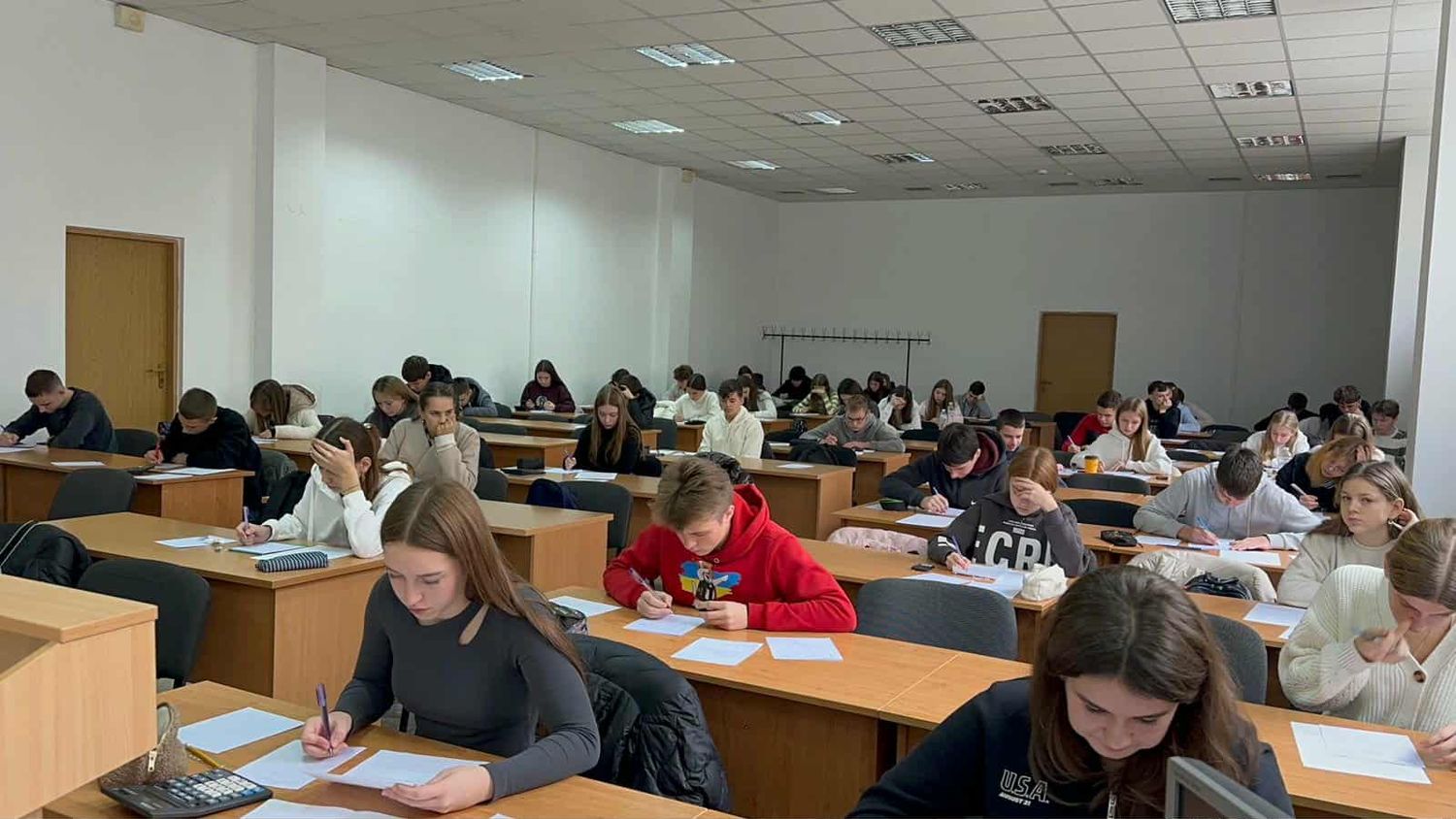 учасники сидять в аудиторії та пишуть