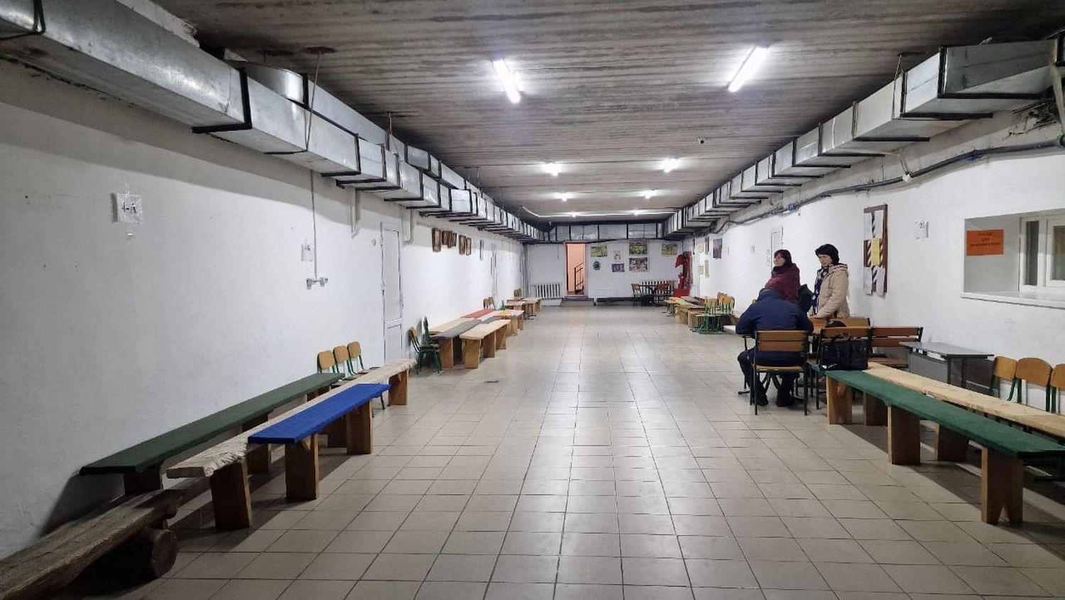 коридор з лавками по боках, на віддалі стоять люди