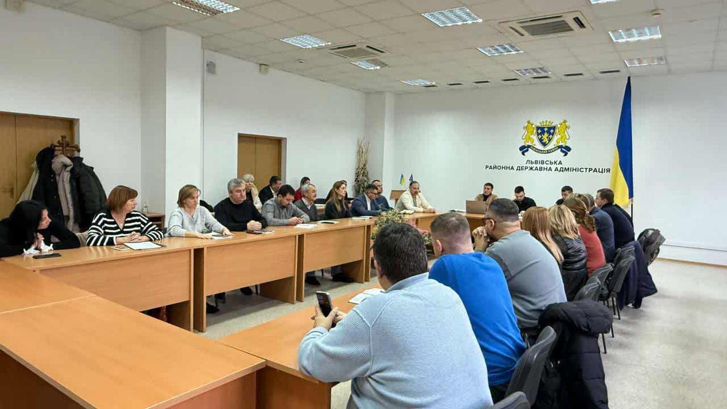 люди сидять за столом, на стіні герб львівського району та напис "ЛЬВІВСЬКА РАЙОННА ДЕРЖАВНА АДМІНІСТРАЦІЯ"