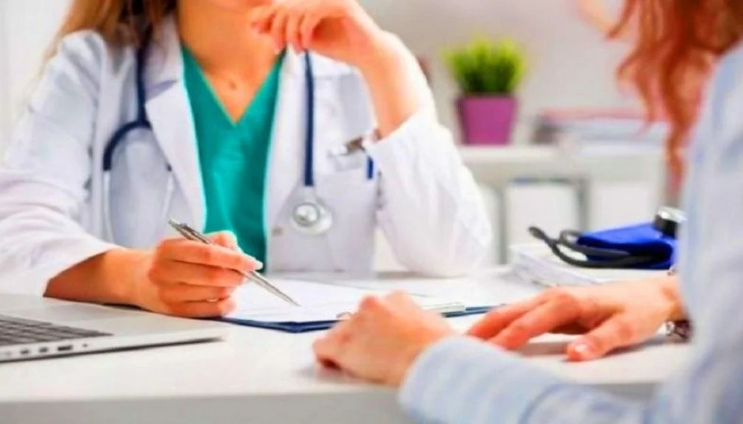 лікарка за столом, на якому лежать документи