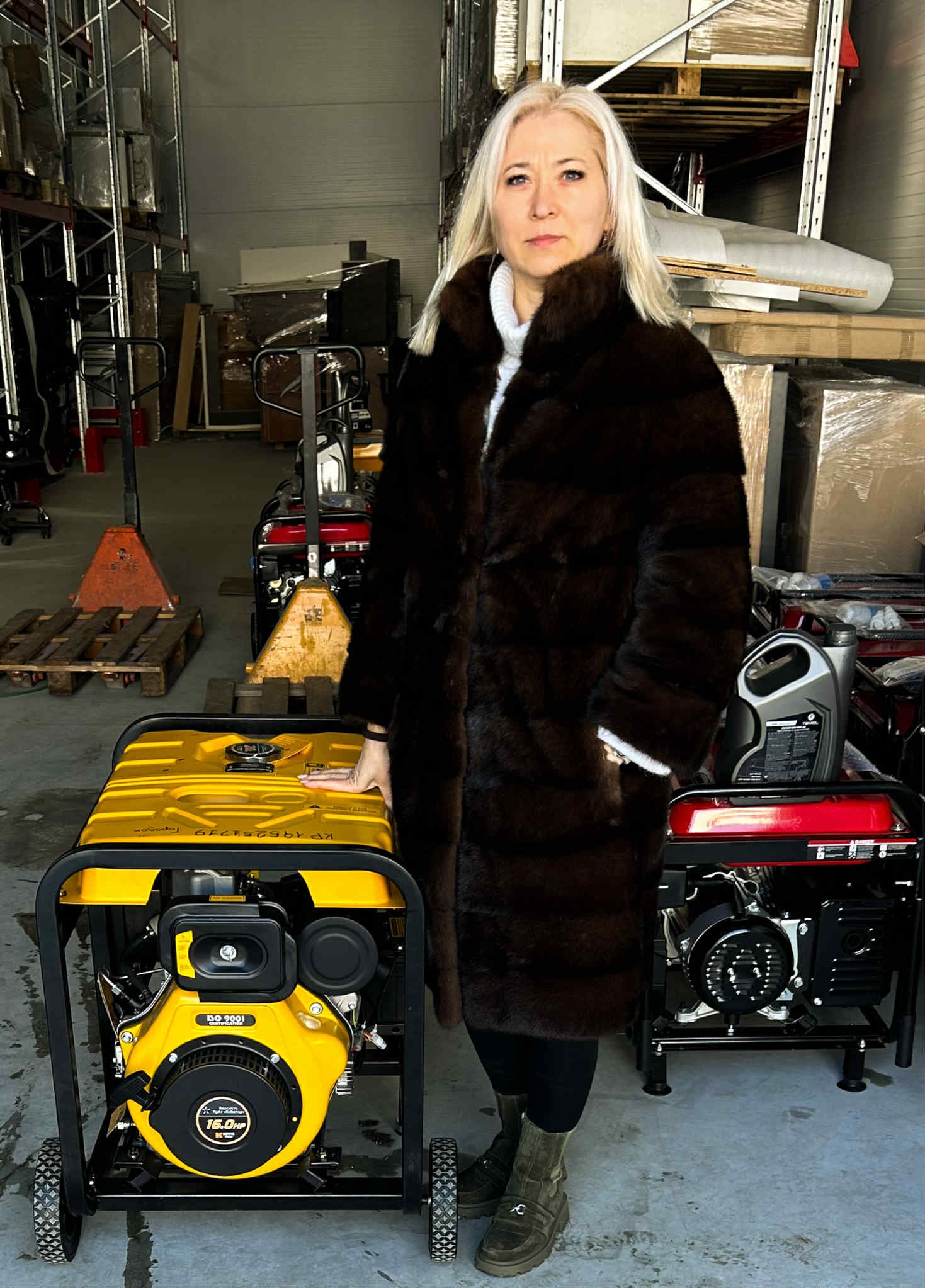 жінка стоїть у приміщенні зі стелажами біля генераторів