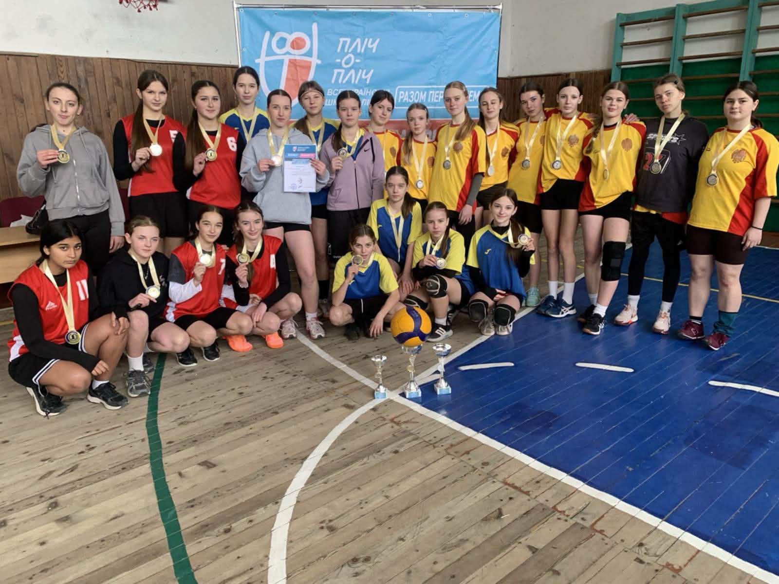 дівчата стоять в спортзалі з кубками та медалями