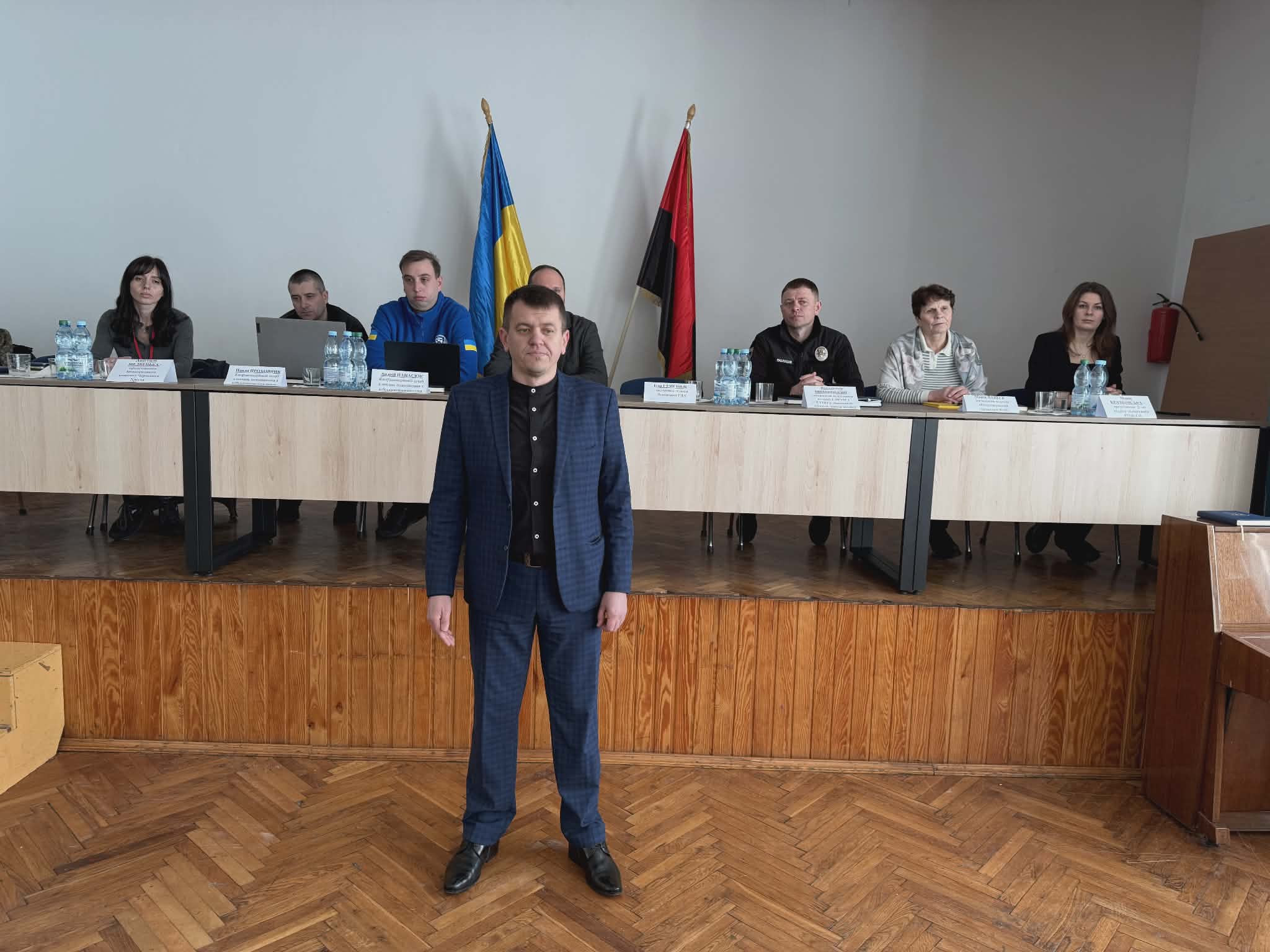 людина стоїть перед сценою, де за стором сидять люди